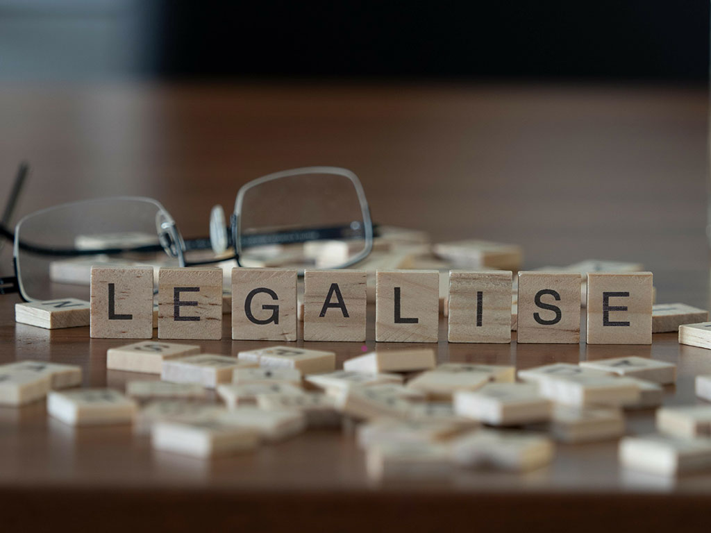 legalise word or concept represented by wooden letter tiles on a wooden table with glasses and a book